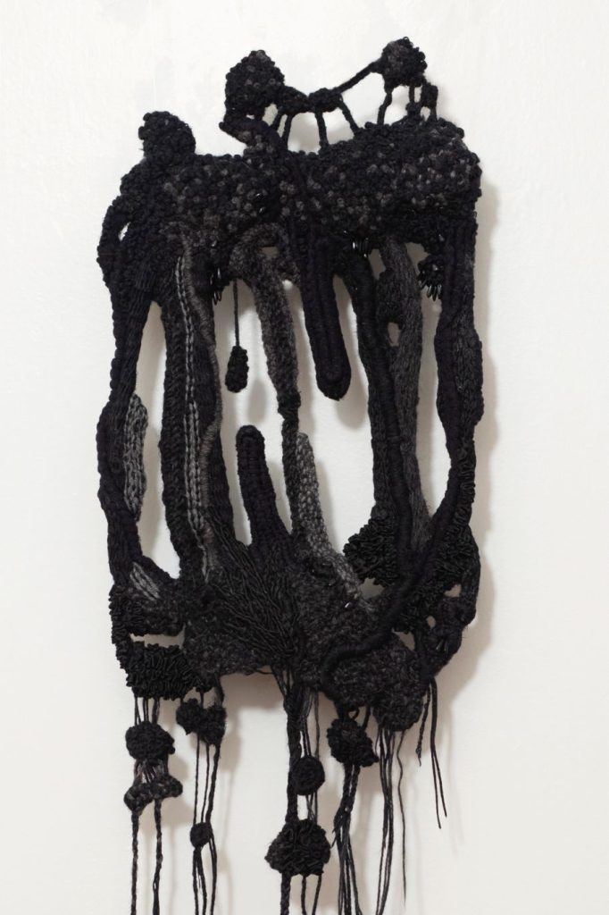 Abstract knitted art structure in black with openings in the middle