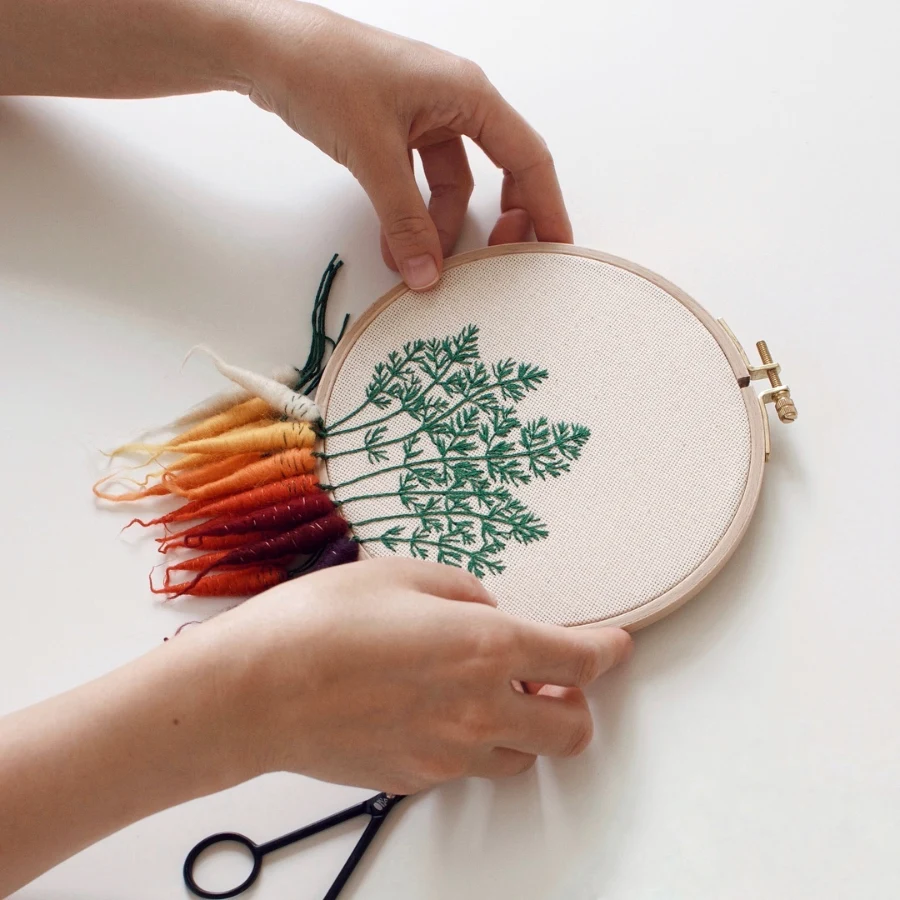 Veselka Bulkan embroidered carrots dangle from the embroidery hoop
