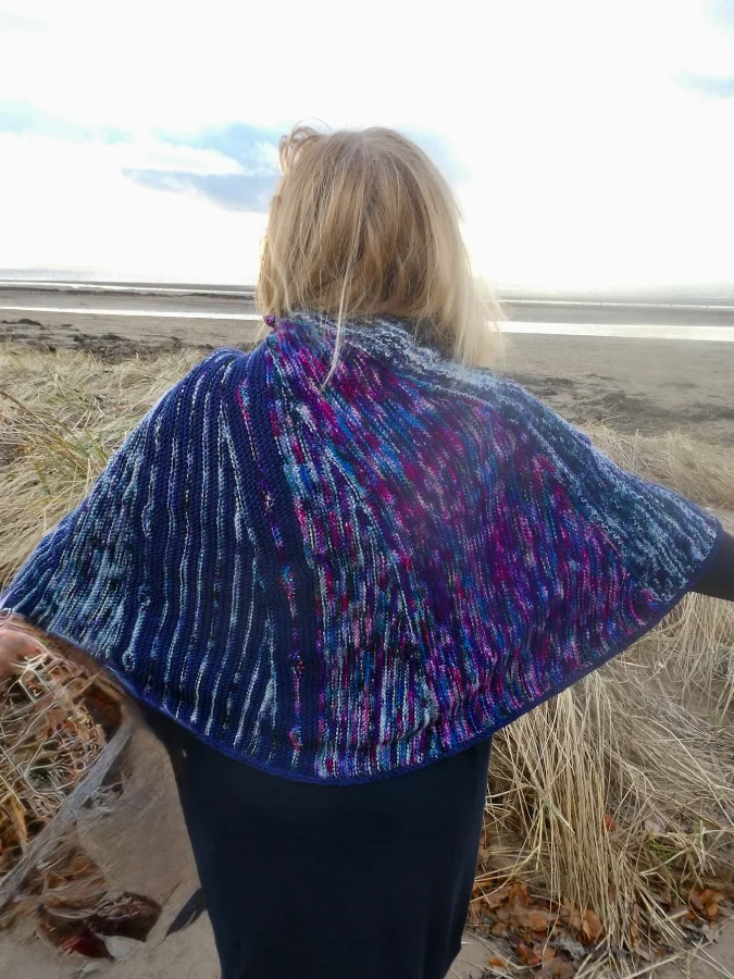 Knitting Skill Stage 3 graduate Rhona Arthur, proudly displying her knitted shawl cloak