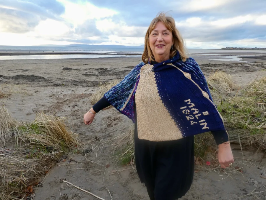 Knitting Skill Stage 3 graduate Rhona Arthur, proudly displaying her knitted shawl cloak